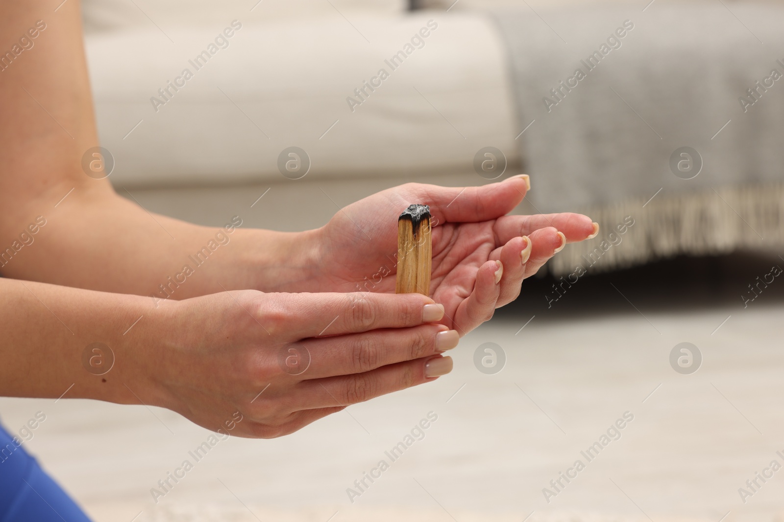 Photo of Woman with smoldering palo santo stick at home, closeup