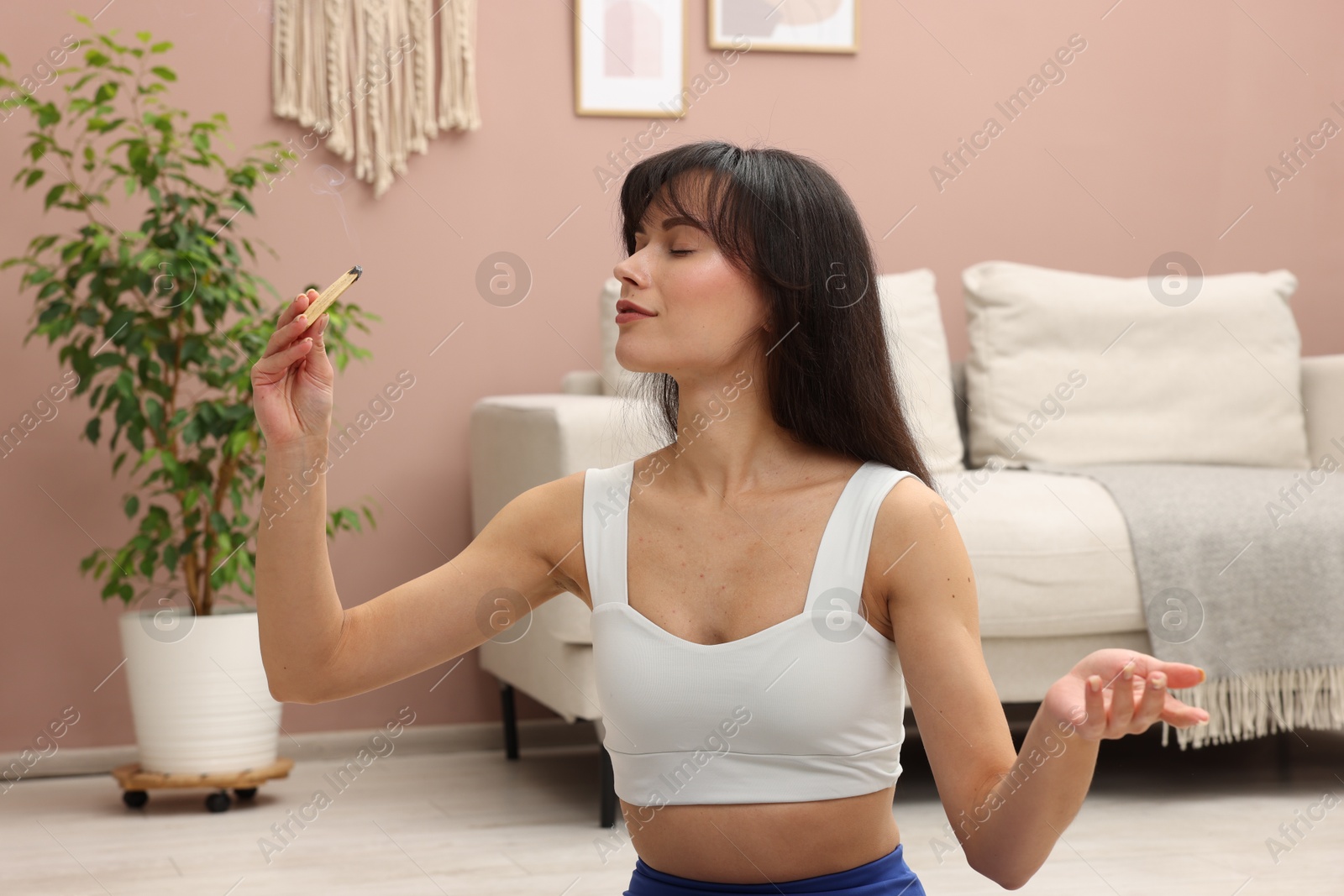 Photo of Woman with smoldering palo santo stick at home