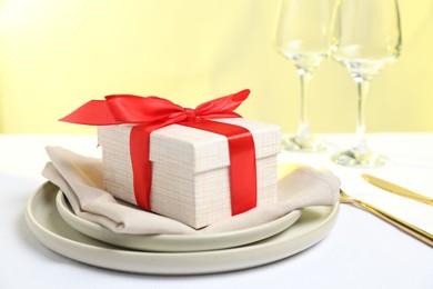 Gift and setting for romantic dinner on white background, closeup