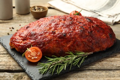 Photo of Delicious turkey meatloaf with tomatoes and rosemary on wooden table, closeup