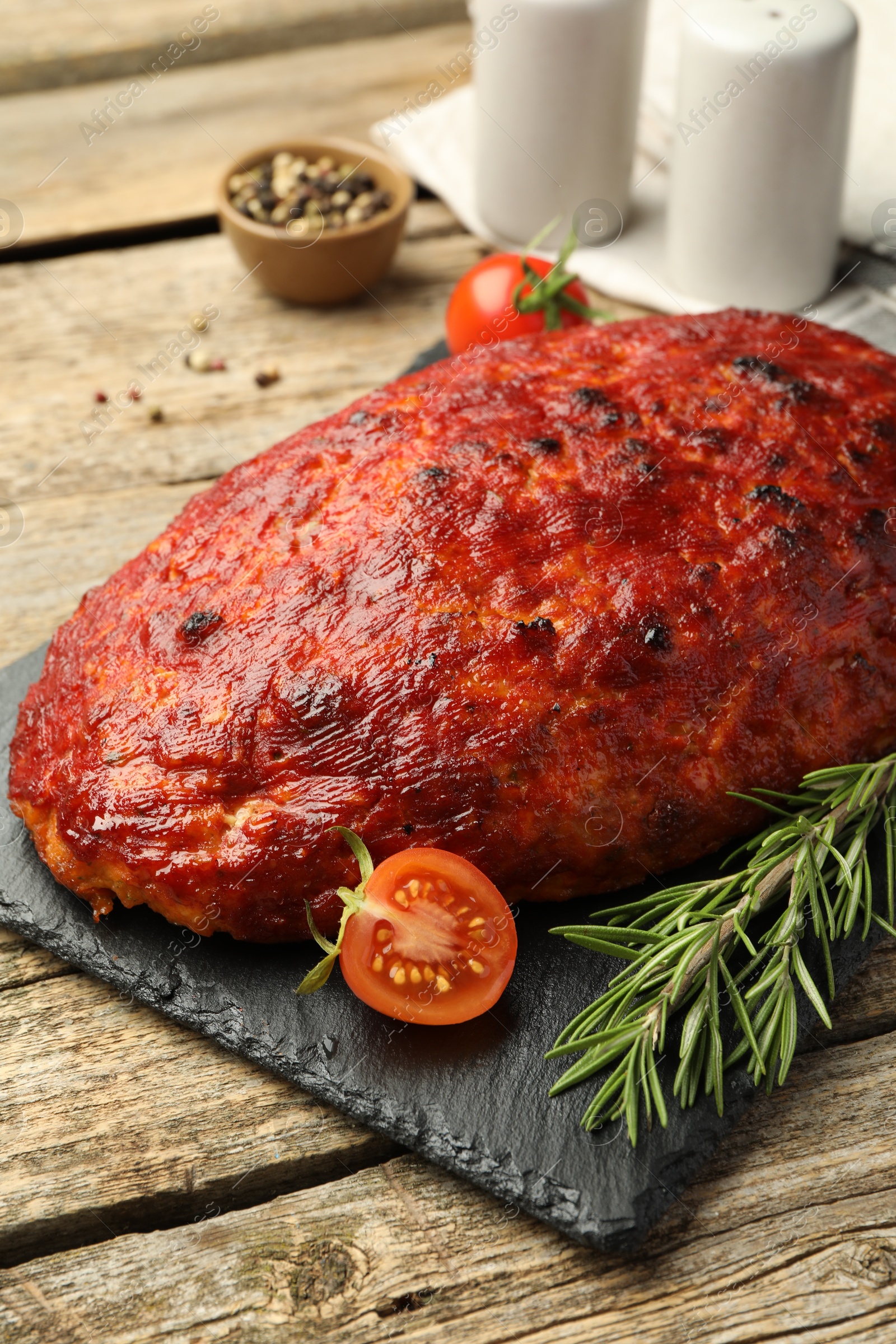 Photo of Delicious turkey meatloaf with tomatoes and rosemary on wooden table