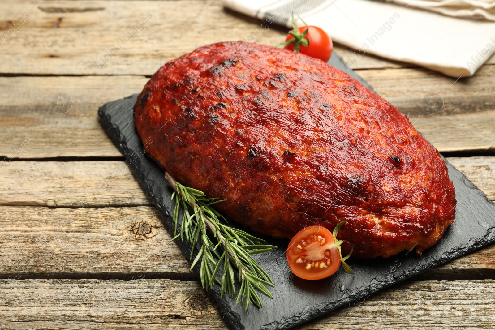 Photo of Delicious turkey meatloaf with tomatoes and rosemary on wooden table