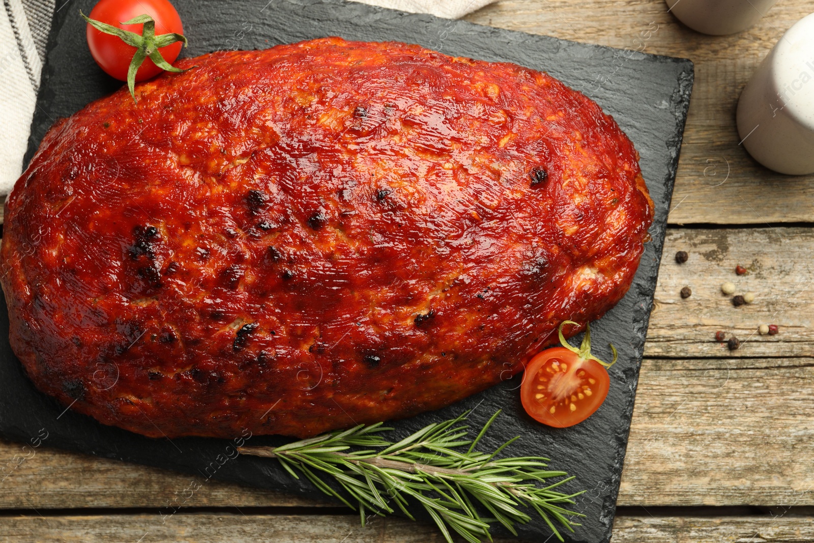 Photo of Delicious turkey meatloaf with tomatoes and rosemary on wooden table, top view