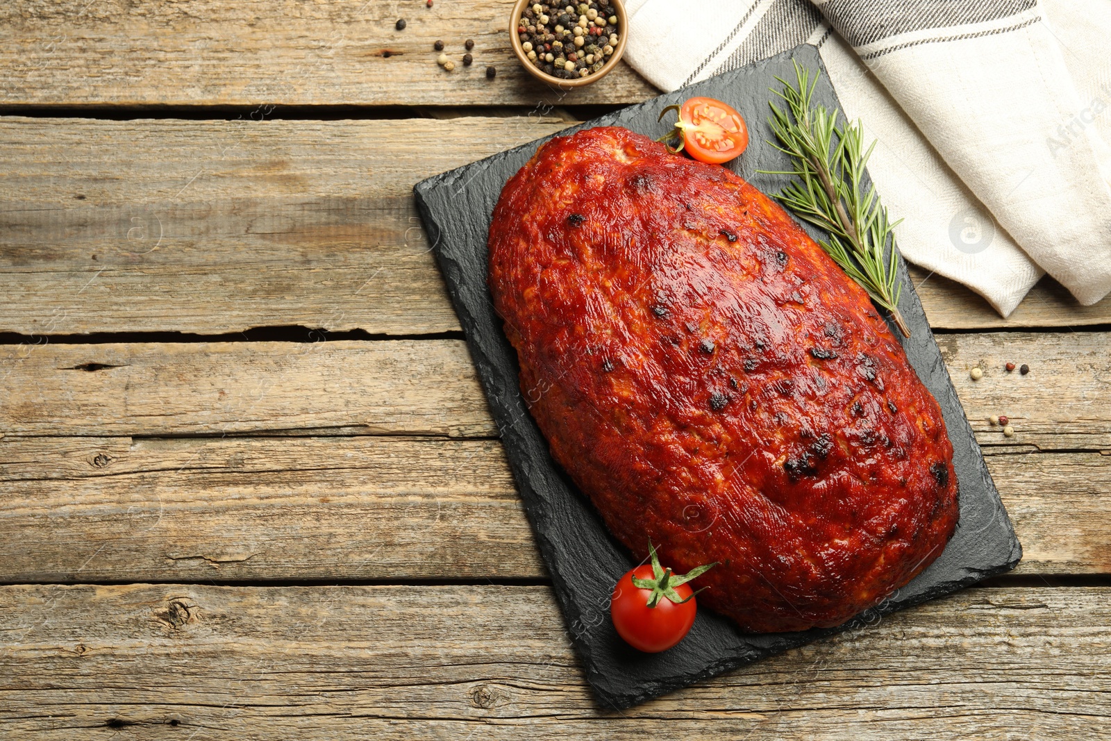 Photo of Delicious turkey meatloaf with tomatoes and rosemary on wooden table, top view. Space for text