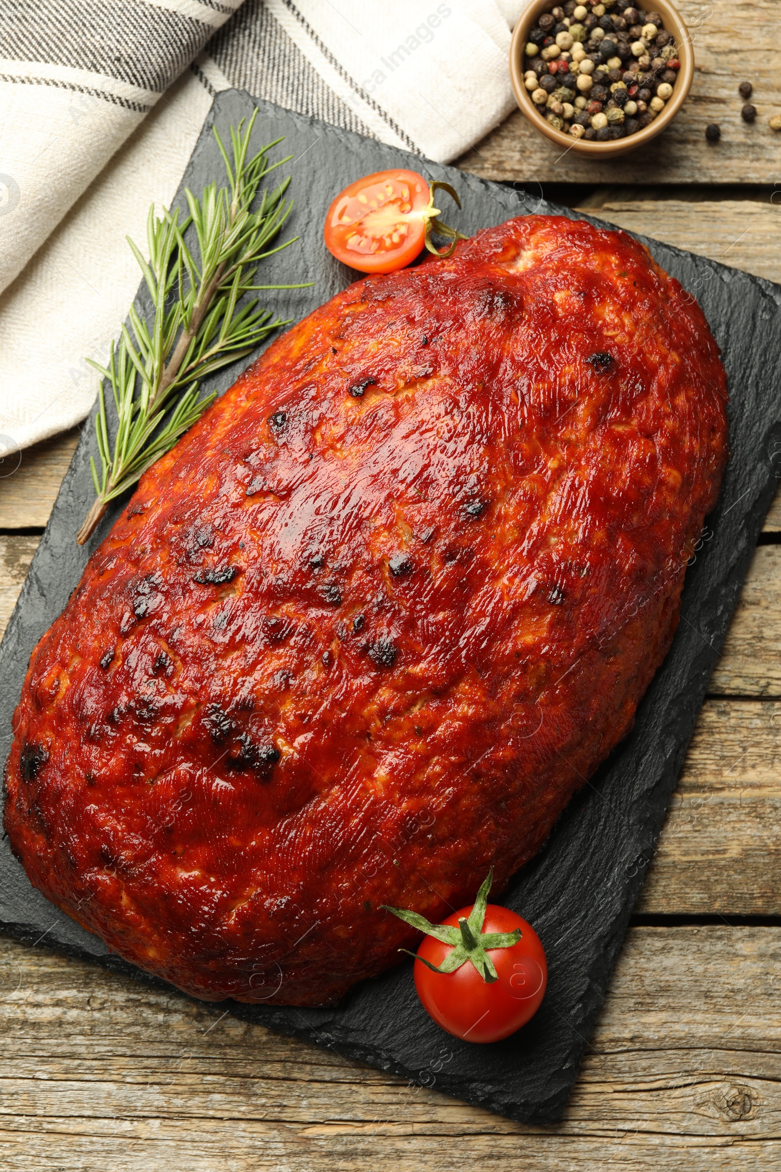 Photo of Delicious turkey meatloaf with tomatoes and rosemary on wooden table, top view