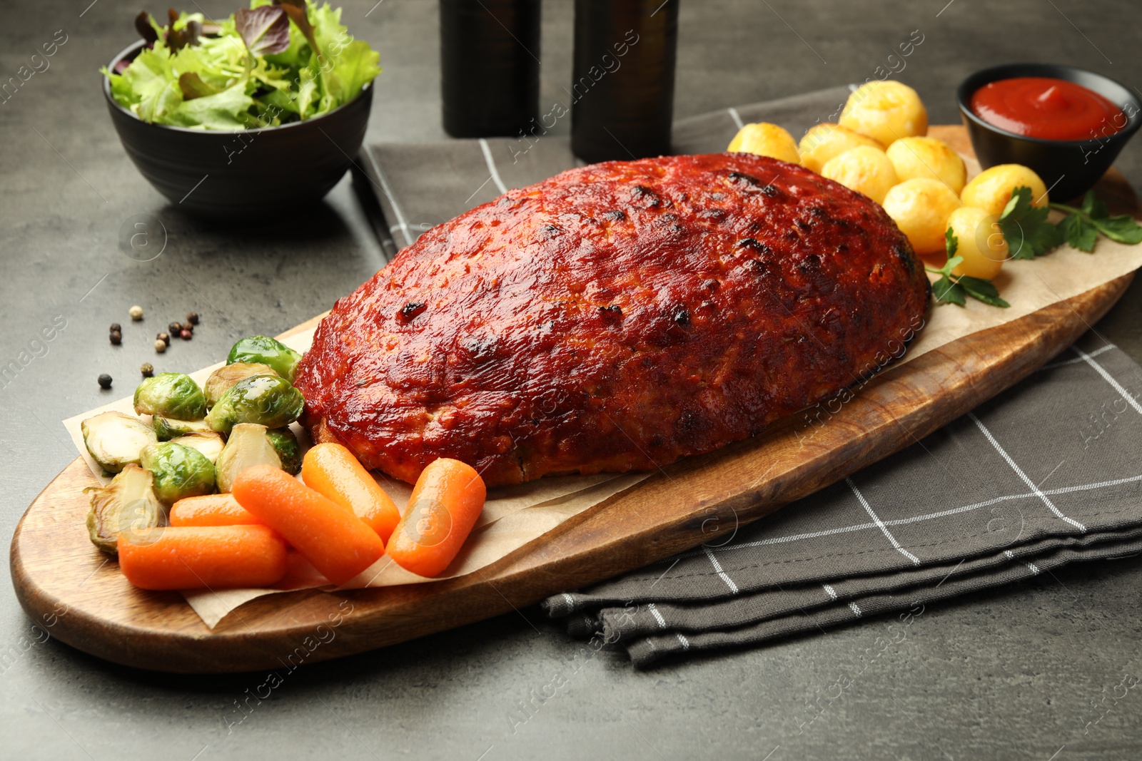 Photo of Delicious turkey meatloaf with vegetables on grey table, closeup