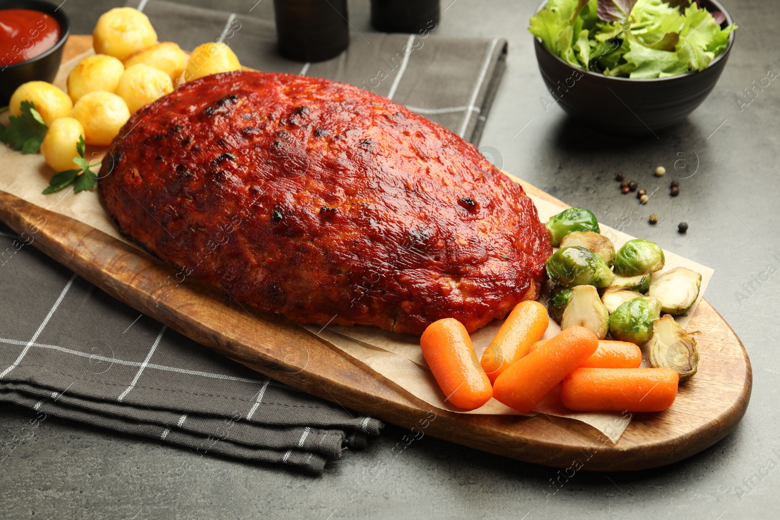 Photo of Delicious turkey meatloaf with vegetables on grey table, closeup