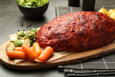 Photo of Delicious turkey meatloaf with vegetables on grey table, closeup