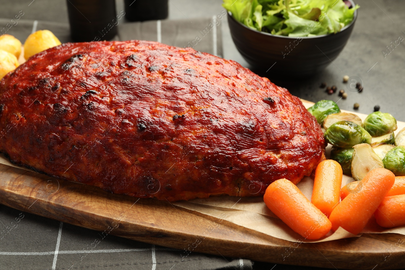 Photo of Delicious turkey meatloaf with vegetables on grey table, closeup