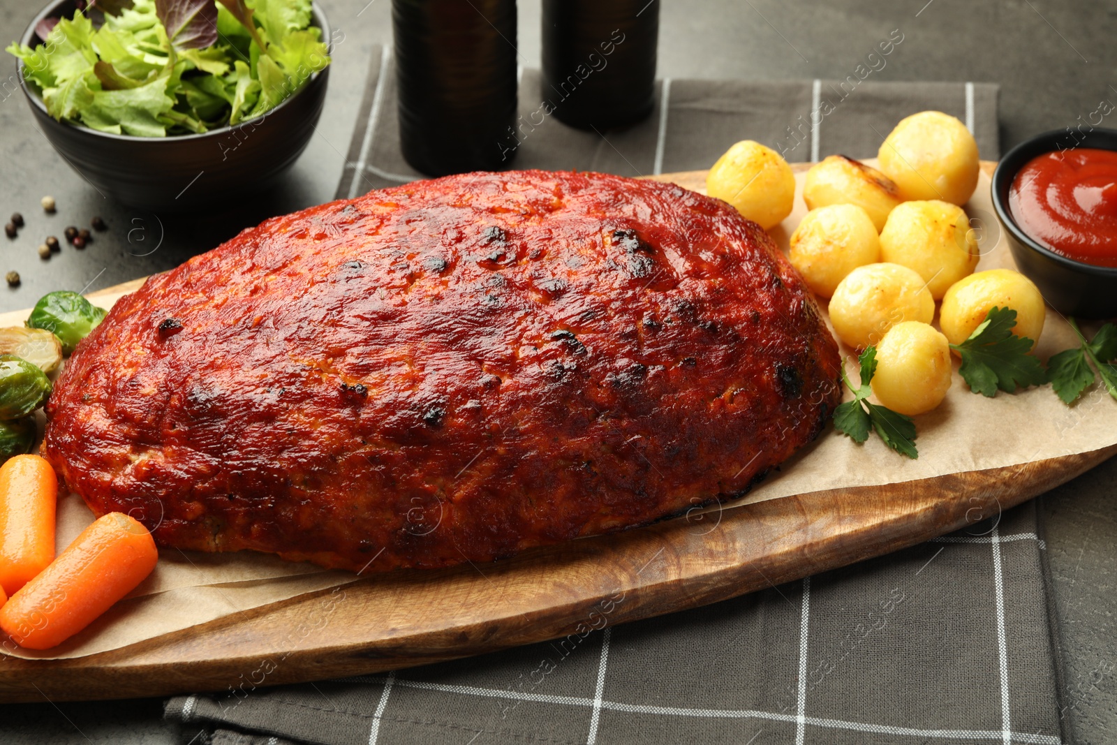 Photo of Delicious turkey meatloaf with vegetables on grey table, closeup