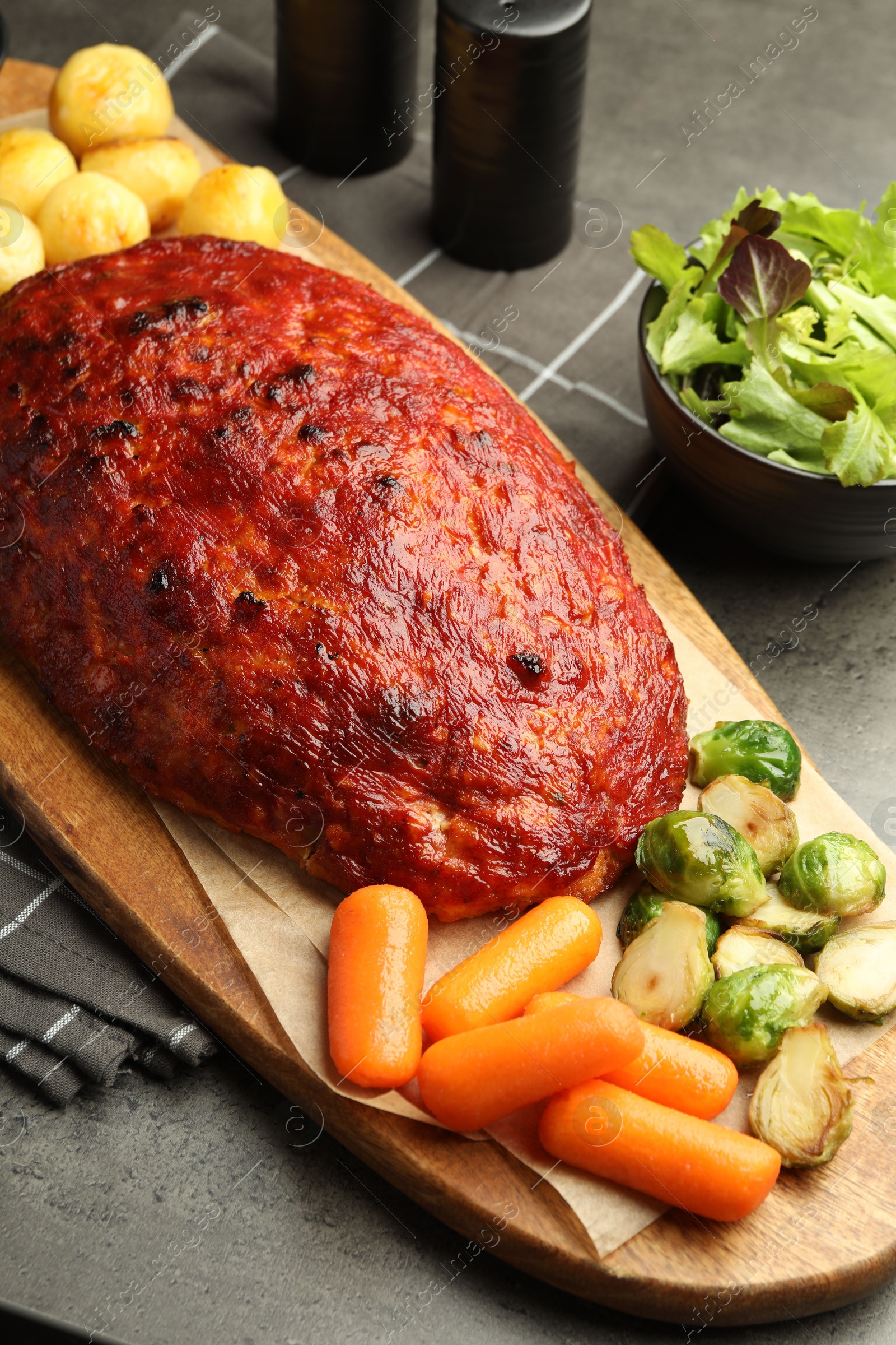 Photo of Delicious turkey meatloaf with vegetables on grey table, closeup