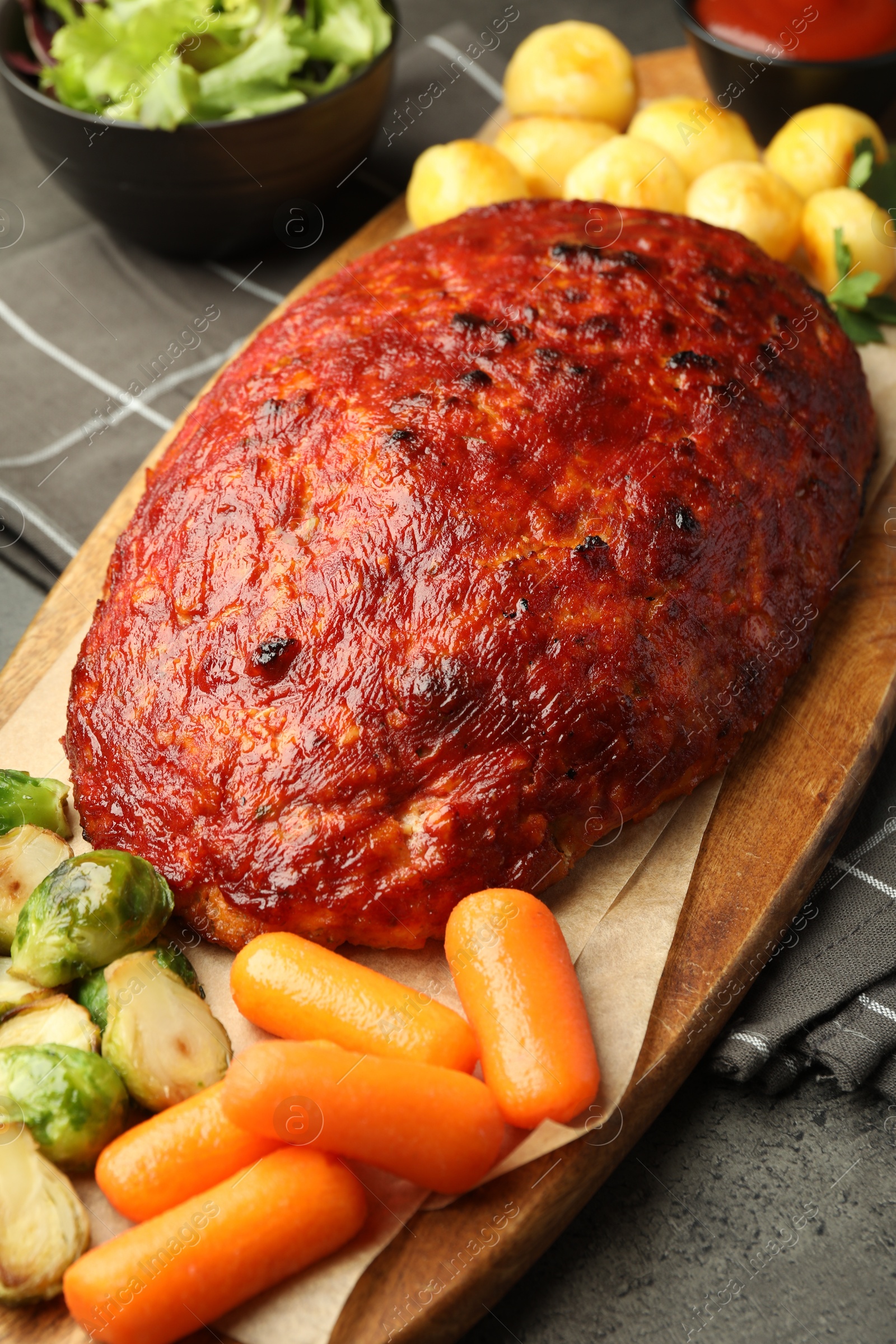 Photo of Delicious turkey meatloaf with vegetables on grey table, closeup