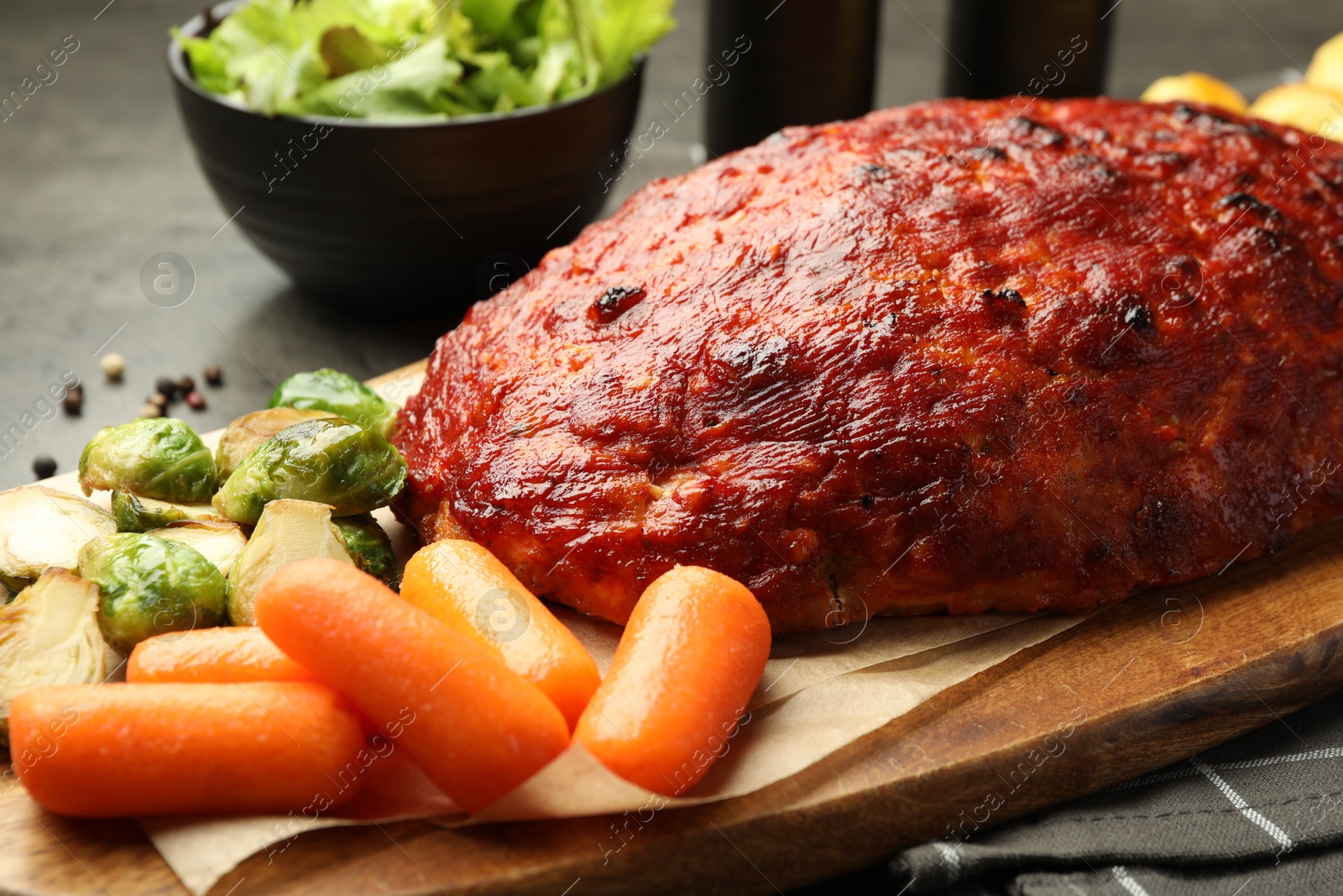 Photo of Delicious turkey meatloaf with vegetables on grey table, closeup