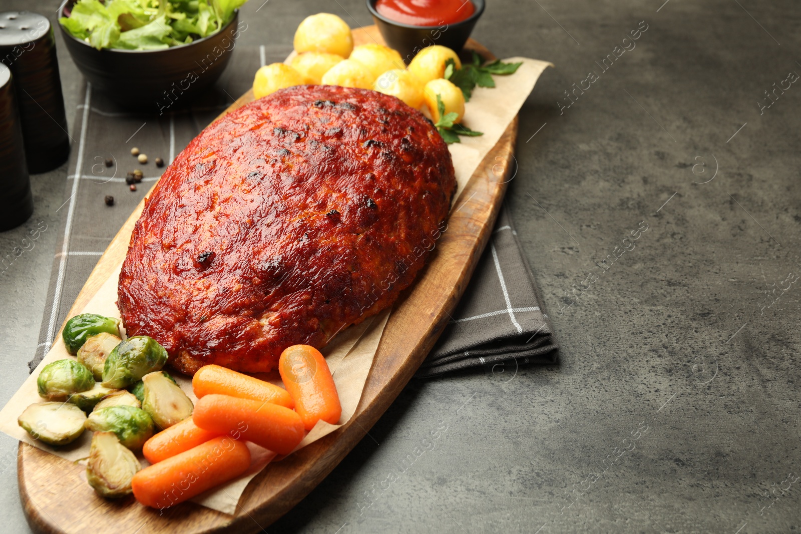 Photo of Delicious turkey meatloaf with vegetables on grey table, closeup. Space for text