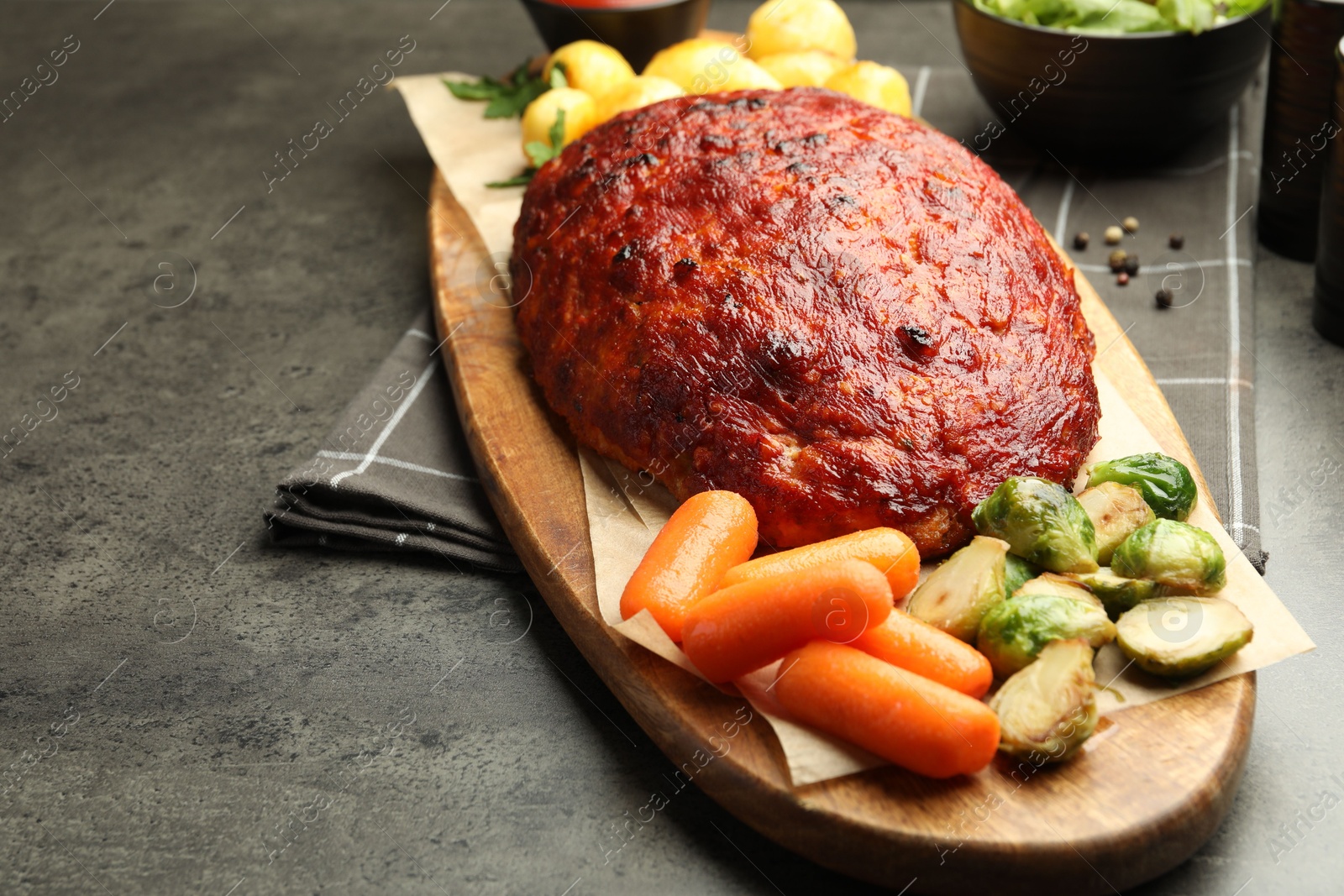 Photo of Delicious turkey meatloaf with vegetables on grey table, closeup. Space for text