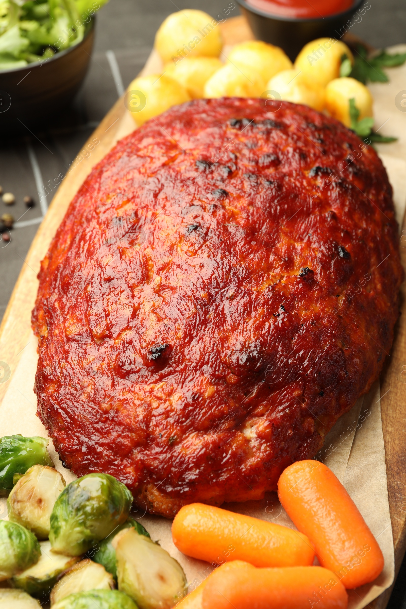 Photo of Delicious turkey meatloaf with vegetables on grey table, closeup