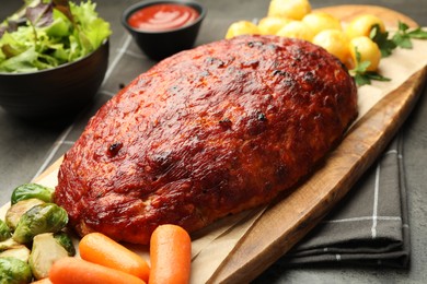 Photo of Delicious turkey meatloaf with vegetables on grey table, closeup