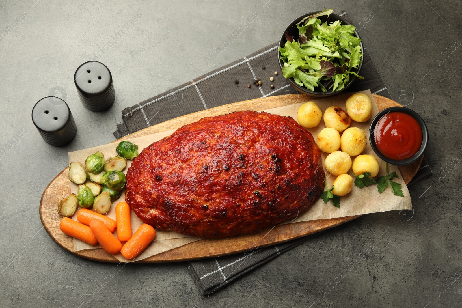 Photo of Delicious turkey meatloaf with vegetables on grey table, top view