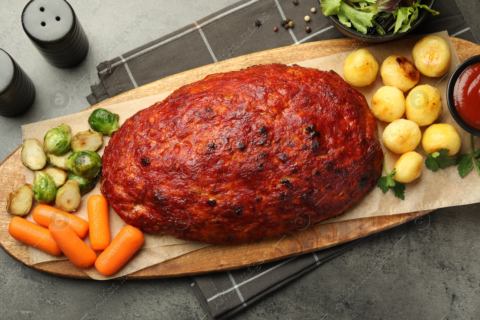 Photo of Delicious turkey meatloaf with vegetables on grey table, top view