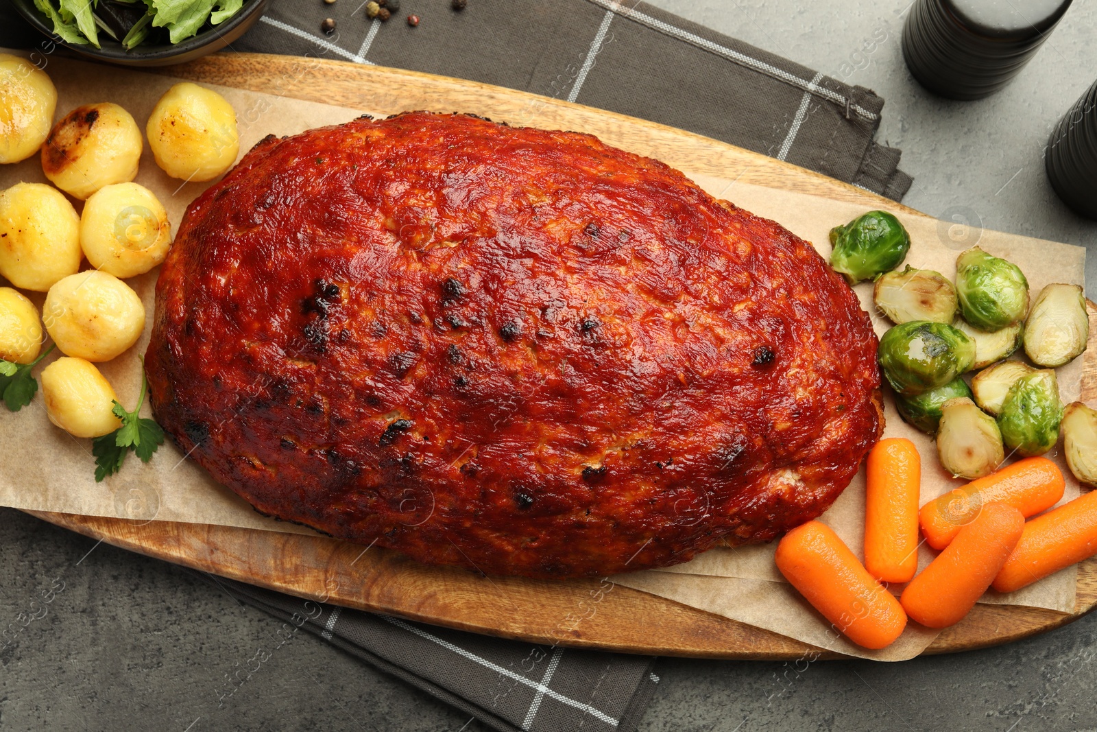 Photo of Delicious turkey meatloaf with vegetables on grey table, top view