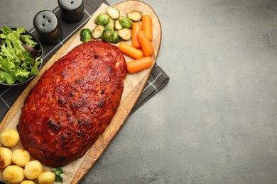 Delicious turkey meatloaf with vegetables on grey table, top view. Space for text