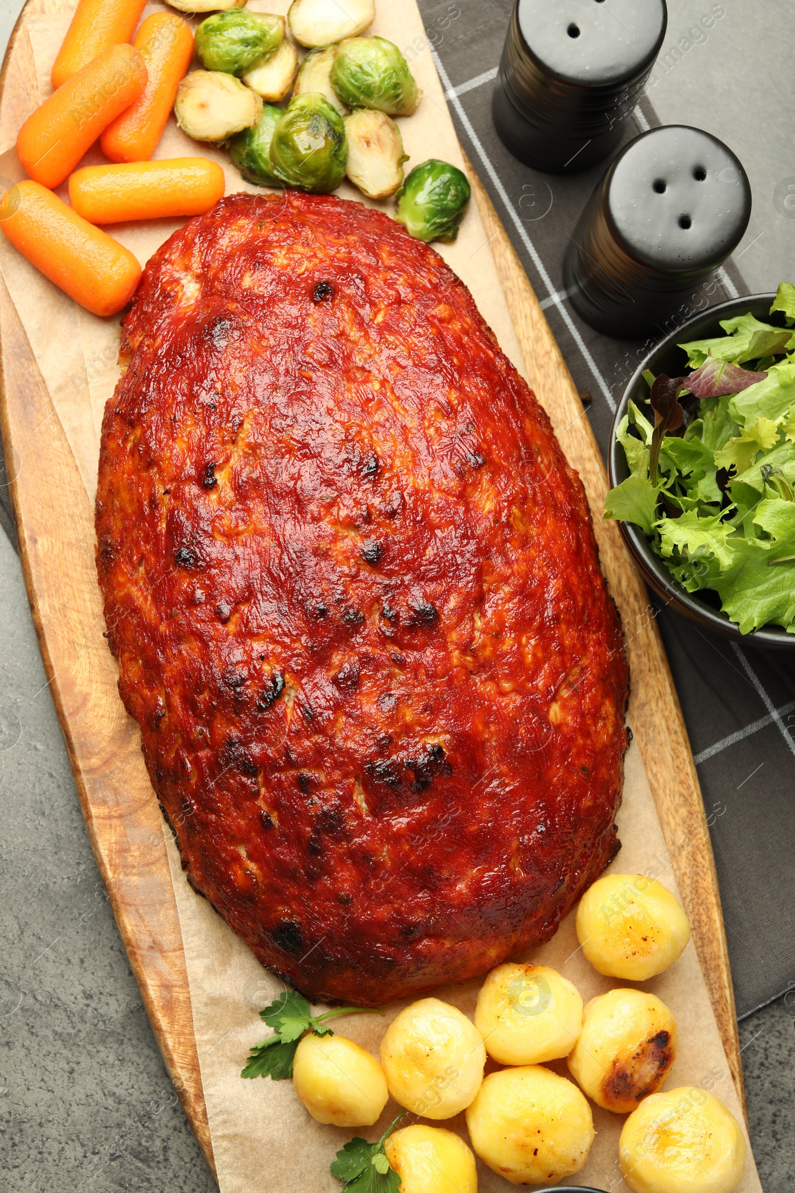 Photo of Delicious turkey meatloaf with vegetables on grey table, top view