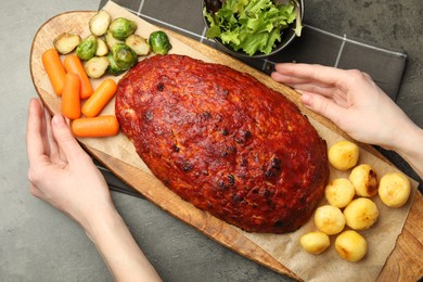 Photo of Woman serving delicious turkey meatloaf at grey table, top view