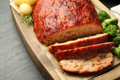 Photo of Delicious turkey meatloaf with vegetables on black table, closeup