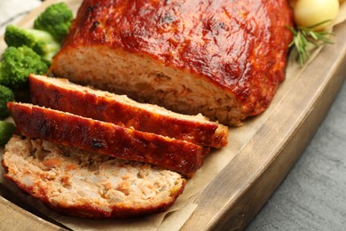 Photo of Delicious turkey meatloaf with vegetables on black table, closeup