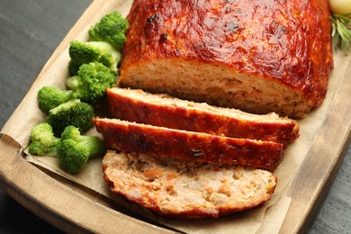 Delicious turkey meatloaf with vegetables on black table, closeup