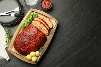 Photo of Delicious turkey meatloaf with vegetables served on black table, flat lay. Space for text