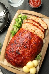 Photo of Delicious turkey meatloaf with vegetables served on black table, flat lay