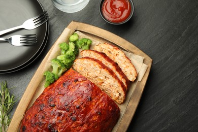 Photo of Delicious turkey meatloaf with vegetables served on black table, flat lay