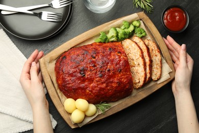 Photo of Woman serving delicious turkey meatloaf at black table, top view