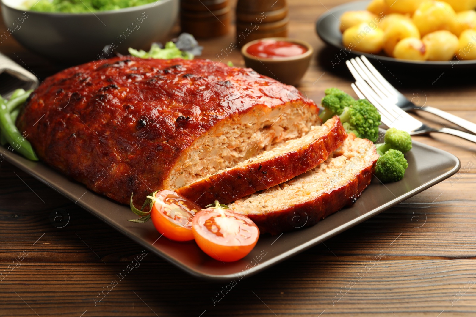 Photo of Delicious turkey meatloaf with vegetables served on wooden table, closeup