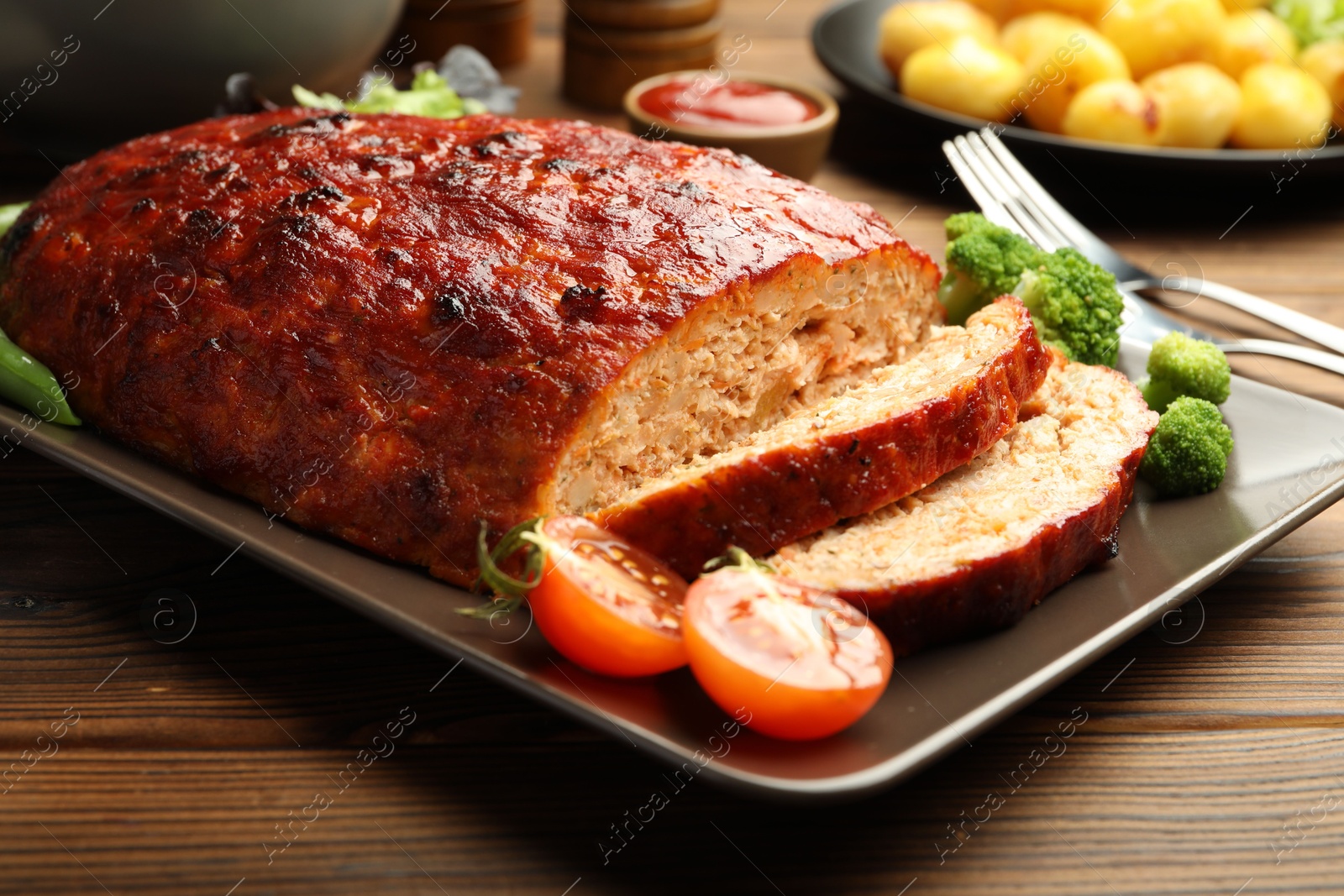 Photo of Delicious turkey meatloaf with vegetables served on wooden table, closeup