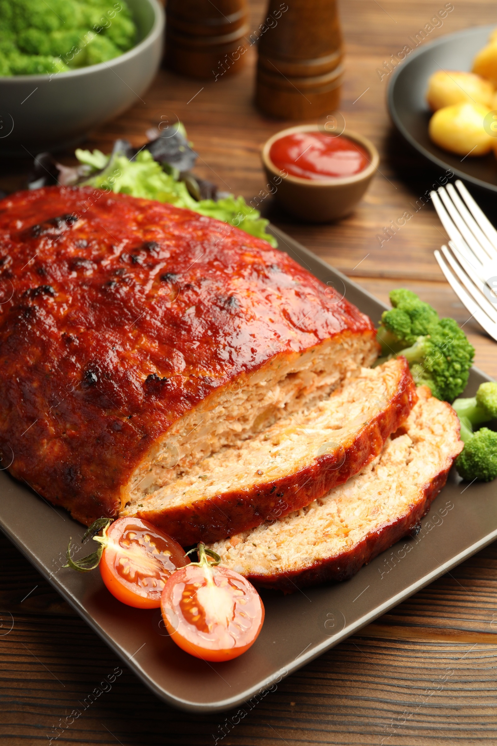 Photo of Delicious turkey meatloaf with vegetables on wooden table