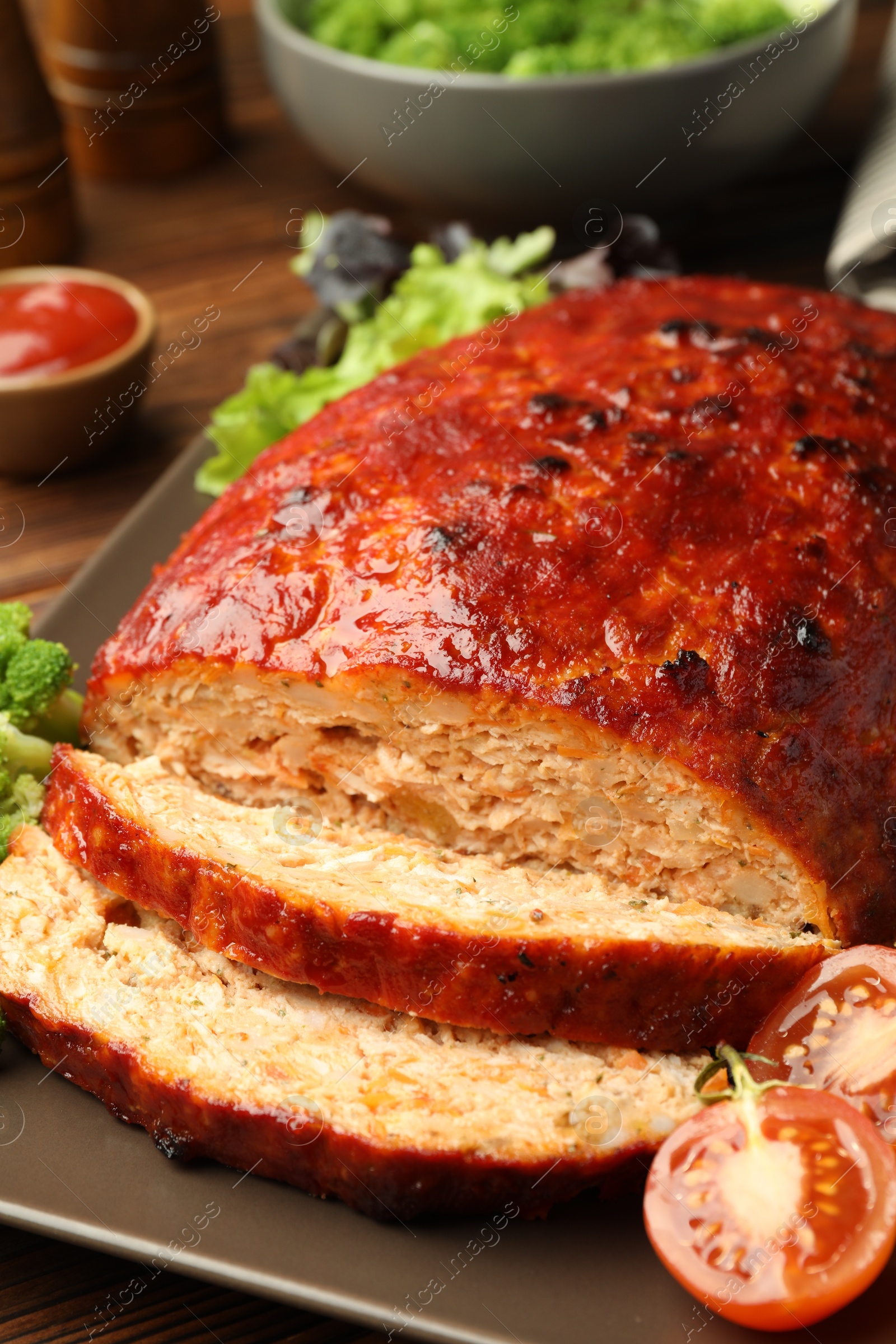 Photo of Delicious turkey meatloaf with vegetables on wooden table, closeup