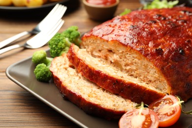 Photo of Delicious turkey meatloaf with vegetables served on wooden table, closeup