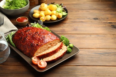 Photo of Delicious turkey meatloaf with vegetables on wooden table. Space for text