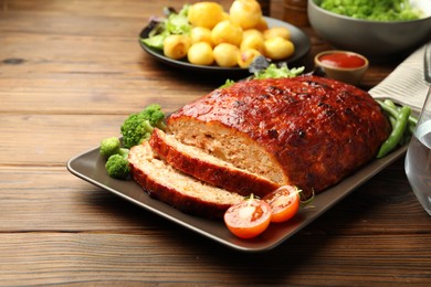 Photo of Delicious turkey meatloaf with vegetables on wooden table