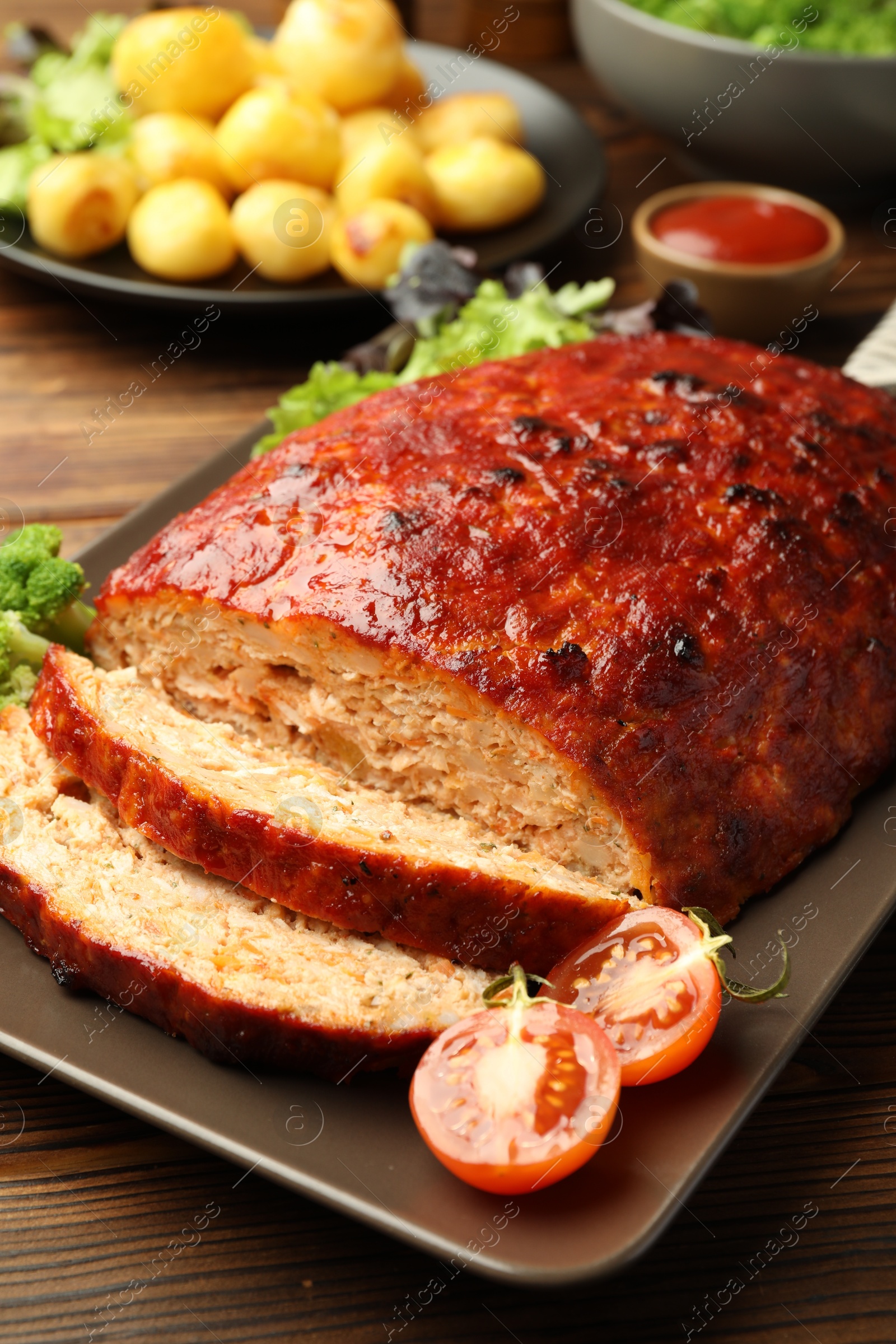 Photo of Delicious turkey meatloaf with vegetables on wooden table, closeup