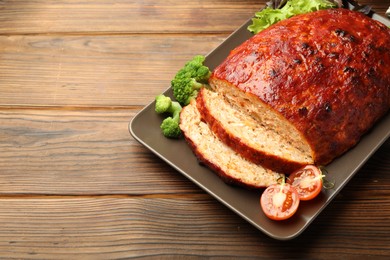 Photo of Delicious turkey meatloaf with vegetables on wooden table. Space for text