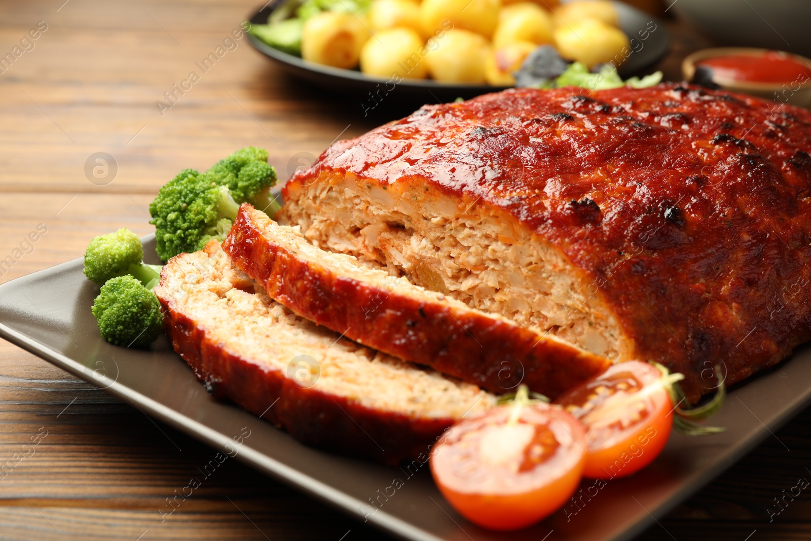 Photo of Delicious turkey meatloaf with vegetables on wooden table, closeup