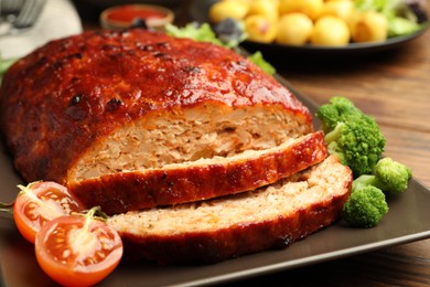 Photo of Delicious turkey meatloaf with vegetables on wooden table, closeup