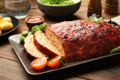 Photo of Delicious turkey meatloaf with vegetables on wooden table, closeup