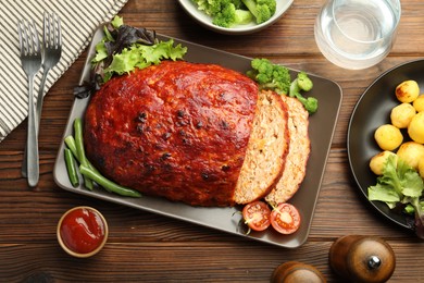 Delicious turkey meatloaf with vegetables served on wooden table, flat lay