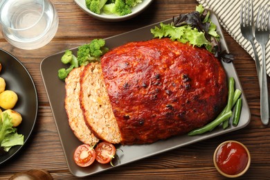 Photo of Delicious turkey meatloaf with vegetables served on wooden table, flat lay