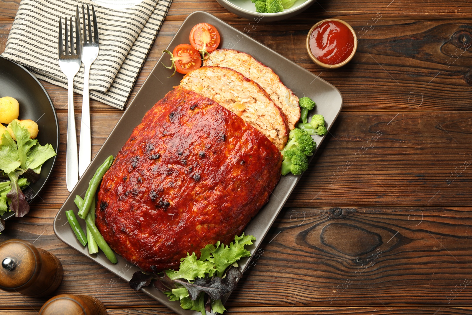 Photo of Delicious turkey meatloaf with vegetables served on wooden table, flat lay. Space for text