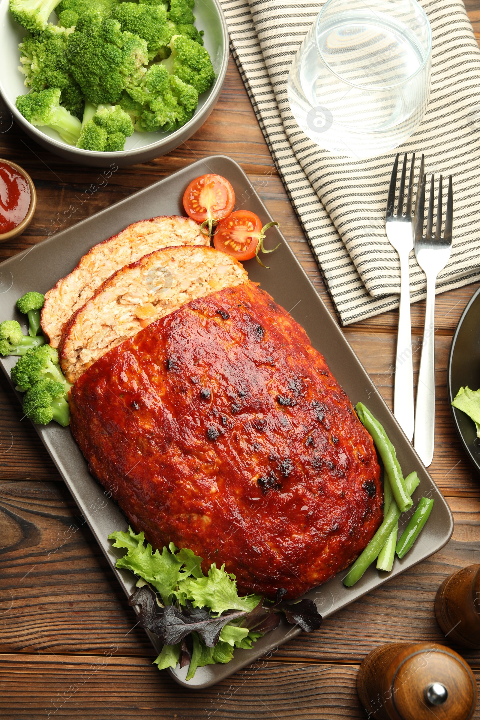 Photo of Delicious turkey meatloaf with vegetables served on wooden table, flat lay